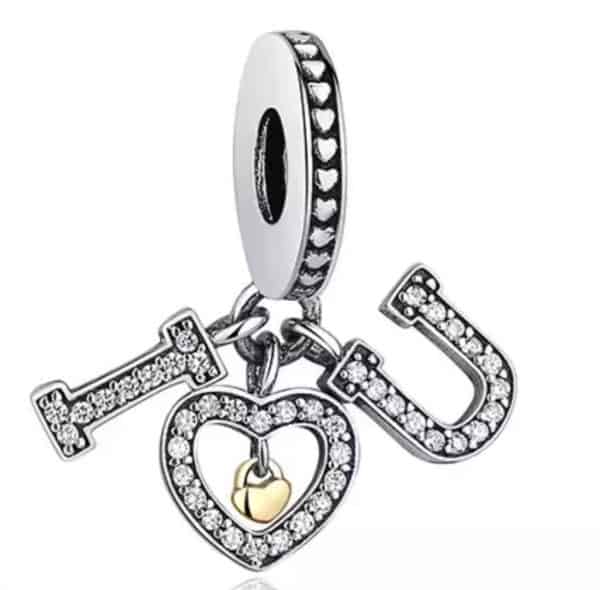 Vooraanzicht van onze nieuw liefdes bedel. De charm heeft de letters I love U hangen in 3 delen. Deze liefdes bedel met i love you is gemaakt van 925 sterling zilver. In de charm zijn hartjes gegraveerd en er hangt een gouden hart in het grote hart dat gemaakt is van zirkonia. Een echte bedel voor valentijn