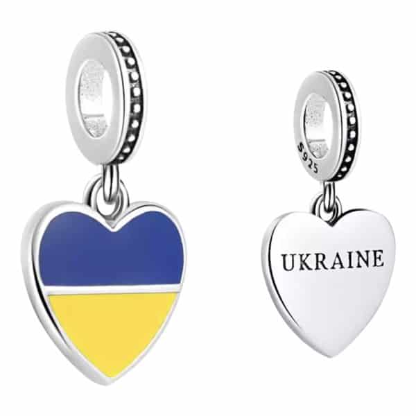 Product Afbeelding Voor en Achterzijde van onze mooie hart vlag charm oekraine. Deze reisbedel heeft blauw en geel emaille die staan voor de vlag van oekraine. Op de achterkant van het hart staat in zwart ukraine gegraveerd. Gemaakt van 925 sterling zilver.
